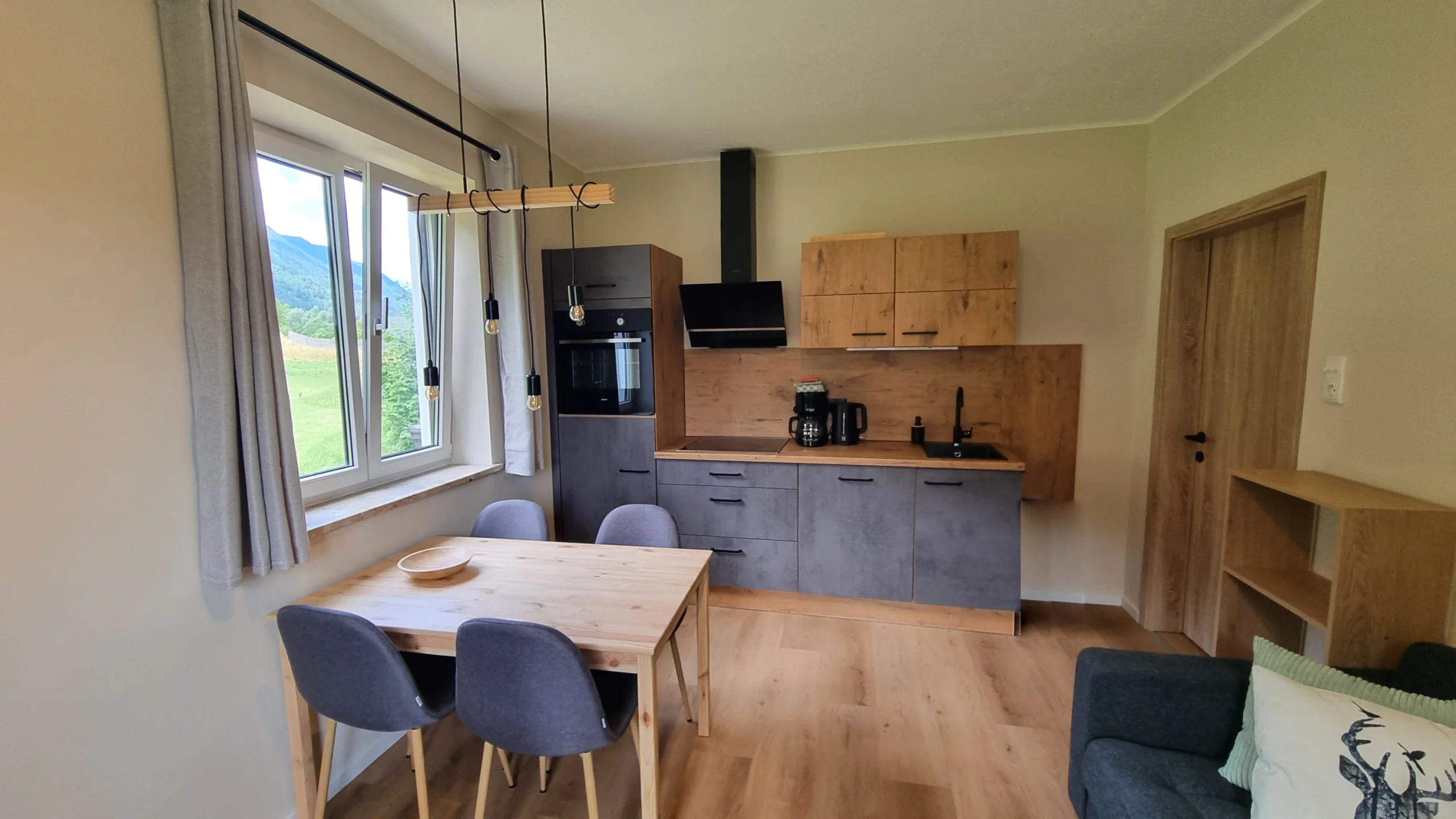 Wohnküche der Ferienwohnung 2 mit Küchenzeile, Esstisch und Fenster mit Blick auf die Berge