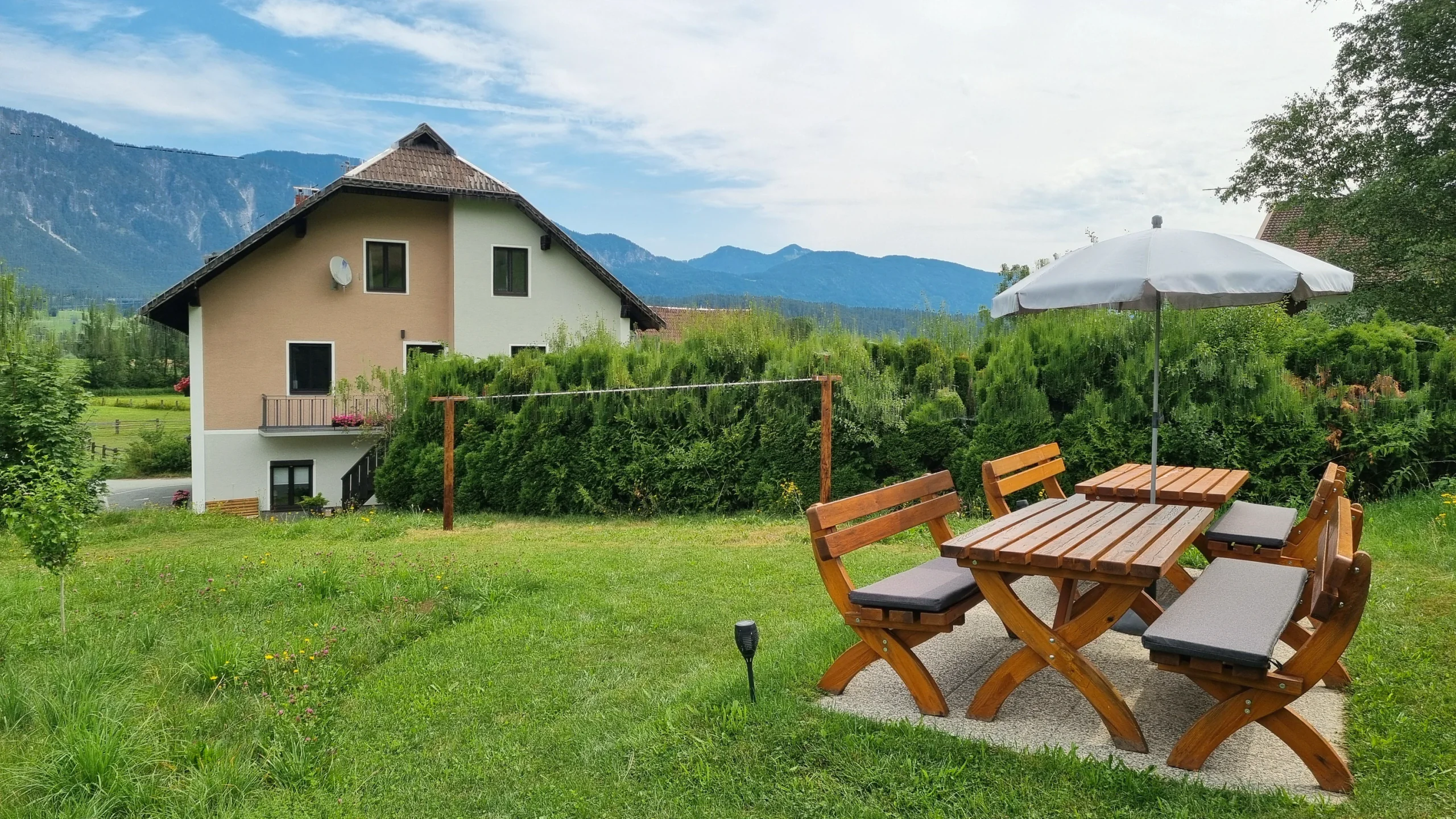 Haus Nampolach mit Garten, Holz-Sitzgruppe unter dem Sonnenschirm und den Gailtaler Bergen dahinter